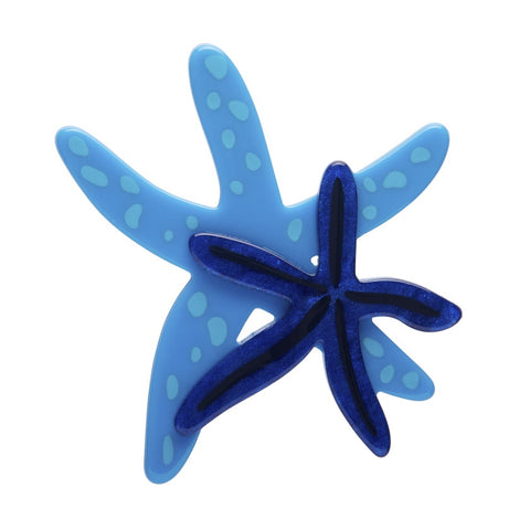 An Erstwilder brooch depicting two blue seastars with layered resin.