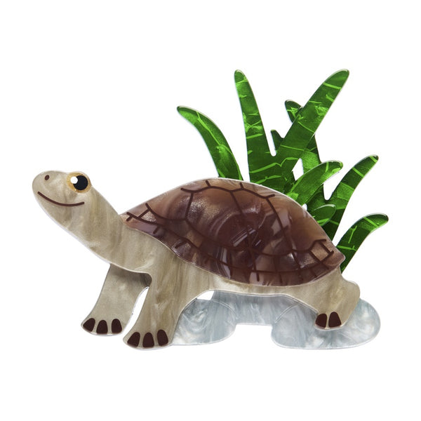 Resin turtle brooch with a brown shell and green leaves on a white background