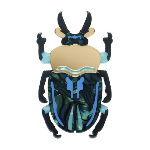 Decorative beetle brooch with green, blue, and black colored resin on a white background
