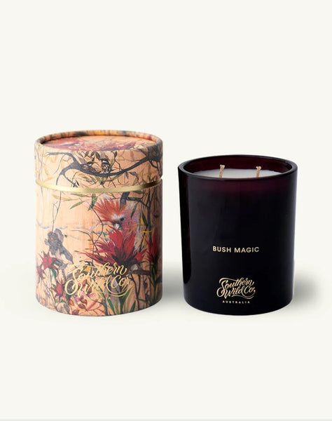 A soy wax candle with a dark glass container, next to a cylindrical paper tube with floral design.