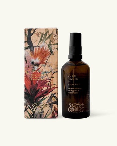 A recyclable amber glass bottle of Bush Magic room mist with a spray pump, next to its signature packaging box with a printed image of a bird and eucalyptus leaves.