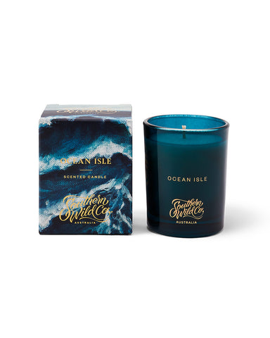 A Southern Wild Co. Ocean Isle Edition II candle in a dark blue glass jar with a label featuring ocean waves.