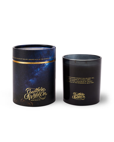 A dark blue glass candle alongside a cylindrical container with a starry night sky design.