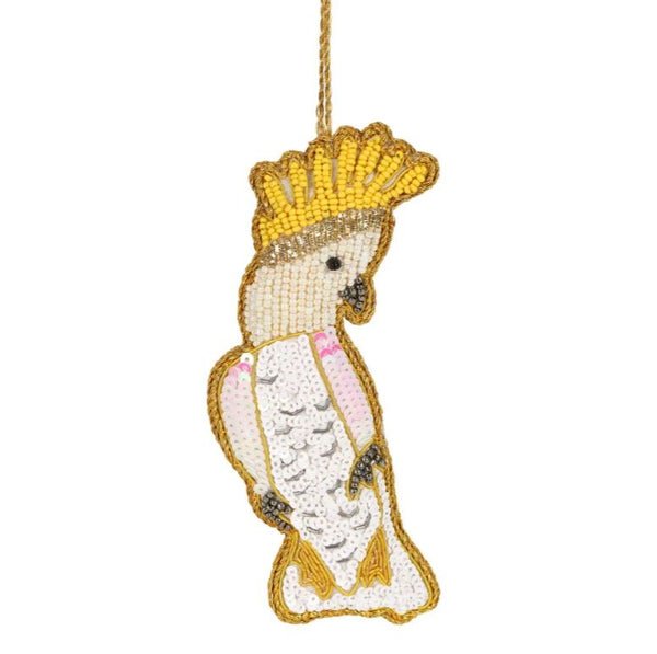 A sequinned and beaded Christmas decoration by Vixen & Velvet shaped like a Sulphur Crested Cockatoo in gold, yellow and white sequins.