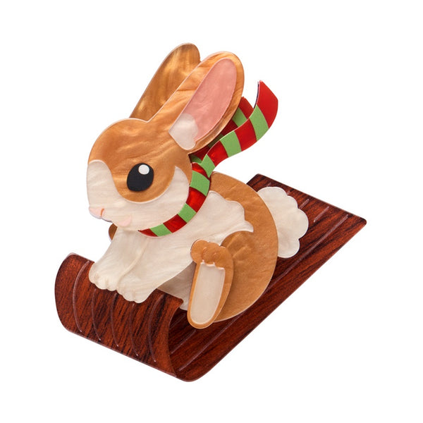 Erstwilder Breezy the Bunny layered brooch features a brown rabbit wearing a green a red scarf on a wooden toboggan.