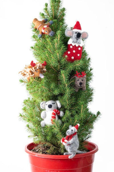 Small Christmas tree with felted animal ornaments on a white background