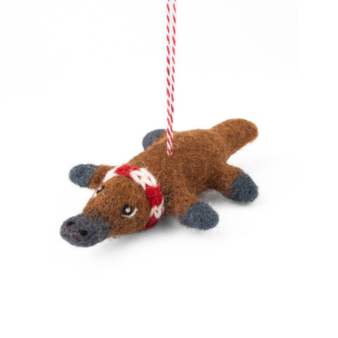 Felted platypus Christmas ornament with a red and white scarf hanging on a white background