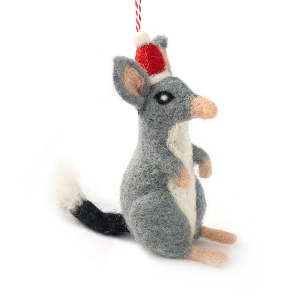 A felted bilby Christmas ornament wearing a Santa hat, hanging from a red and white string against a white background.