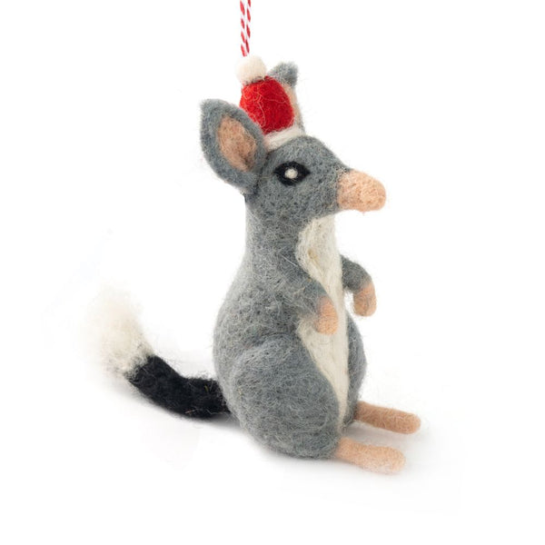 A felted bilby Christmas ornament wearing a Santa hat, hanging from a red and white string against a white background.