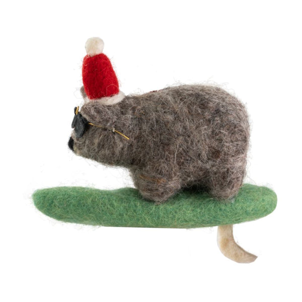 Decorative wombat ornament with a Santa hat, sunglasses riding a green surfboard hanging from a red-and-white string on a white background