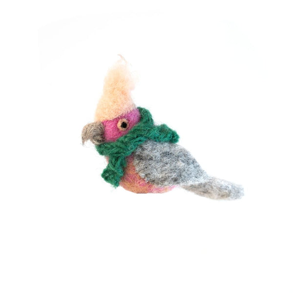 A felted bird ornament wearing a green scarf, hanging from a red and white striped string against a white background.