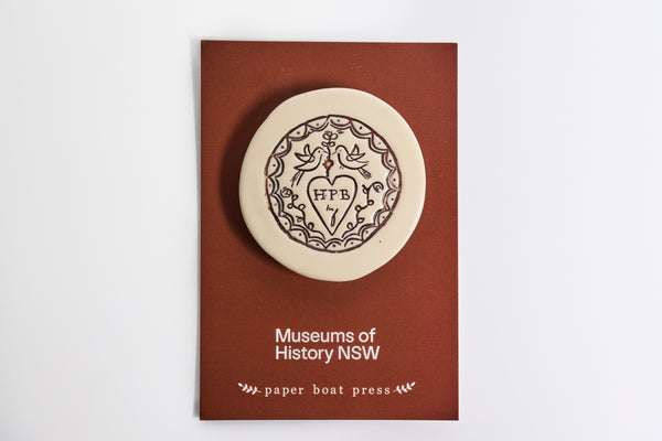 Ceramic magnet with a decorative representation of a Convict Love Token  on a backing card.