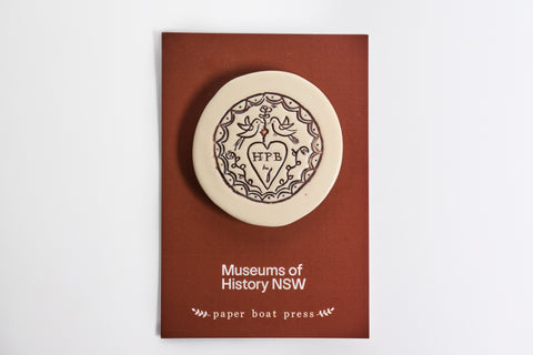 Ceramic magnet with a decorative representation of a Convict Love Token  on a backing card.