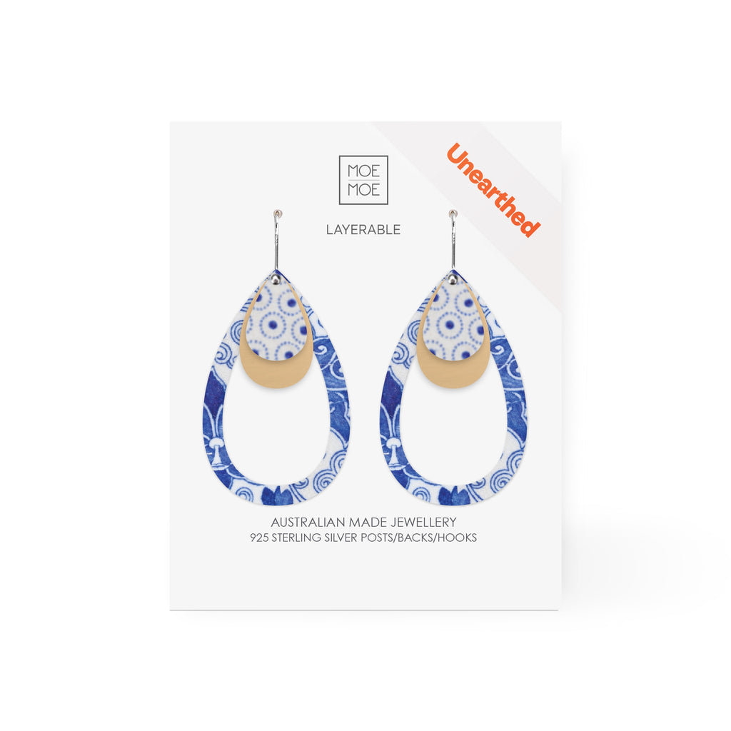 A pair of layered drop earrings featuring a blue and white pattern