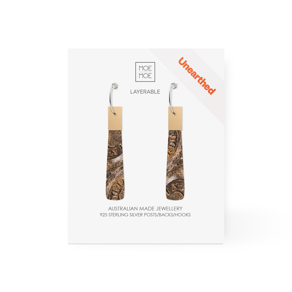 A pair of long drop earrings featuring a pattern created from a digital image from the archaeology collection at Museum of Sydney