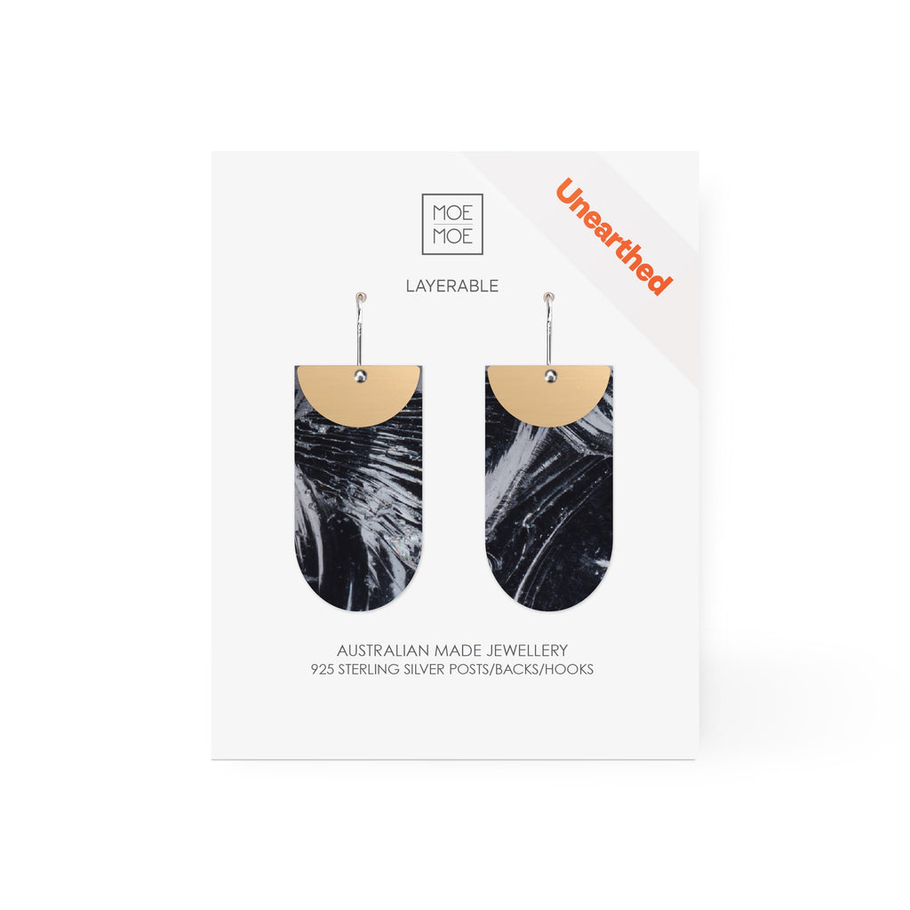 A pair of tab shaped earrings featuring a black and white abstract pattern.