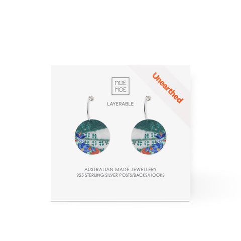 A pair of earrings featuring a green and white pattern