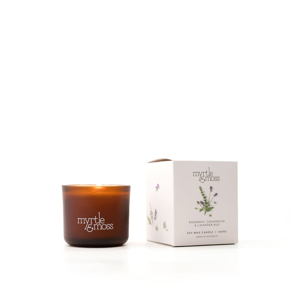 A brown glass soy wax candle with a label that reads 'Myrtle & Moss', alongside its white packaging box with the same brand and product details.