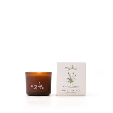 A brown glass soy wax candle with a label that reads 'Myrtle & Moss', alongside its white packaging box with the same brand and product details.
