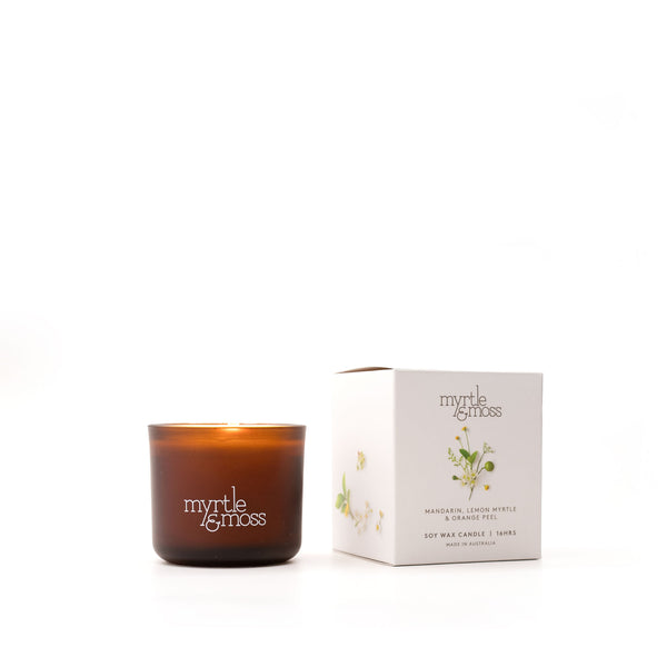 A brown glass soy wax candle with a label that reads 'Myrtle & Moss', alongside its white packaging box with the same brand and product details.