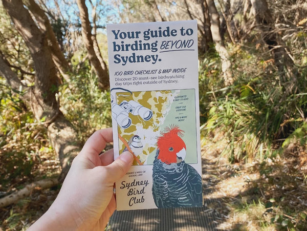 Hand holding a guide to birding beyond Sydney with a natural background