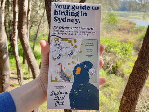 Hand holding a guide to birding in Sydney with a natural background