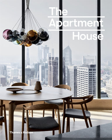 Cover of the book 'The Apartment House' featuring a modern interior with a dining table, chairs, and a striking hanging light fixture, looking out to a cityscape.
