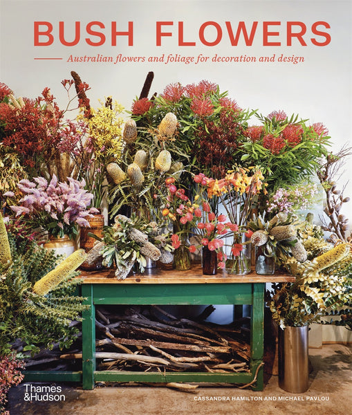 A book cover of 'Bush Flowers' featuring a vibrant display of various Australian native flowers and foliage, arranged in vases and on a rustic table.