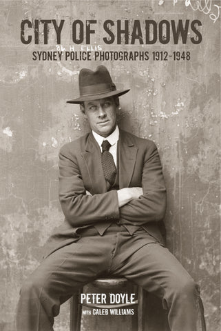 Cover of the book 'City of shadows: Sydney Police Photographs 1912 - 1948' featuring a black and white photograph of a man in a hat and suit, sitting with arms crossed.