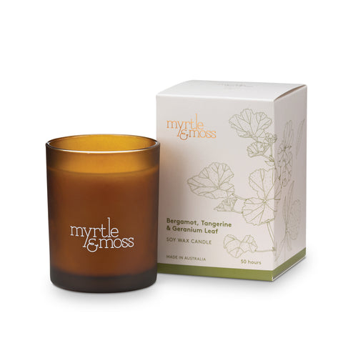 A soy wax candle, in an amber glass jar, scented with bergamot, tangerine, and geranium leaf, with a white box packaging featuring botanical illustrations.
