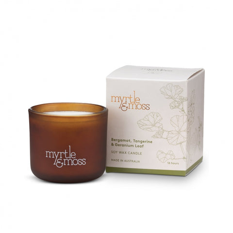 A soy wax candle in a brown glass jar, and a label that reads 'Myrtle & Moss'. The product is displayed alongside a branded box with floral designs.