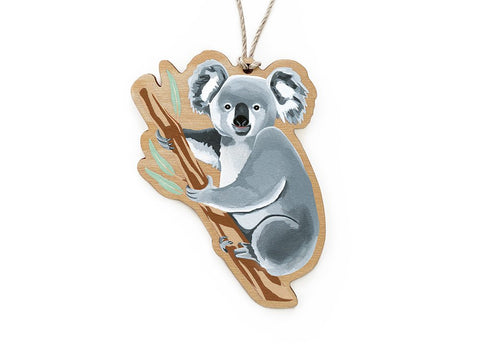 A wooden ornament in the shape of a koala, with a print on one side, hanging from a string.