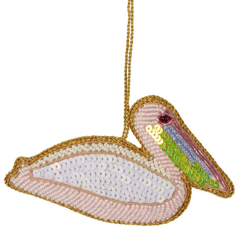 A sequinned decoration in the shape of a pelican, with beige, white, and gold colors, and embellished with red and green details.
