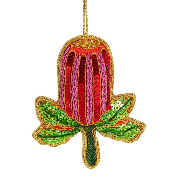A sequined decoration resembling a banksia flower with red, pink and green colors, with a gold trim.