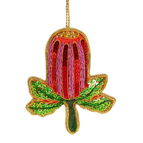 A sequined decoration resembling a banksia flower with red, pink and green colors, with a gold trim.